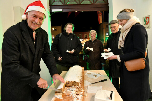 Menschen teilen Weihnachtsstollen bei Feier.