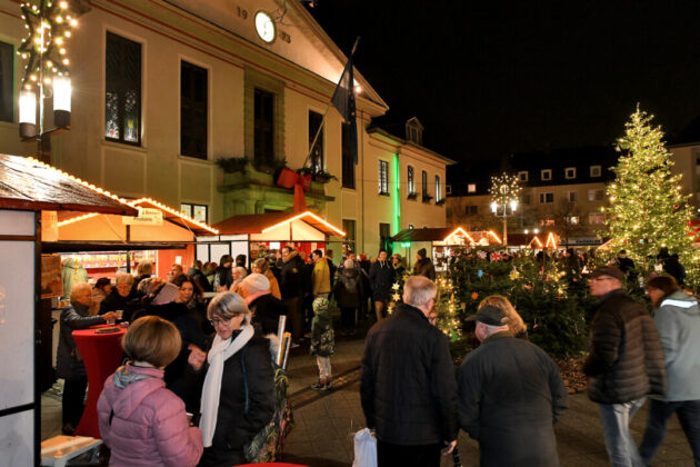 Weihnachtsmarkt bei Nacht mit Besuchern und Beleuchtung.