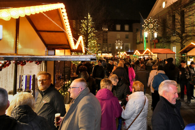 Weihnachtsmarkt bei Nacht mit Menschen und Lichtern