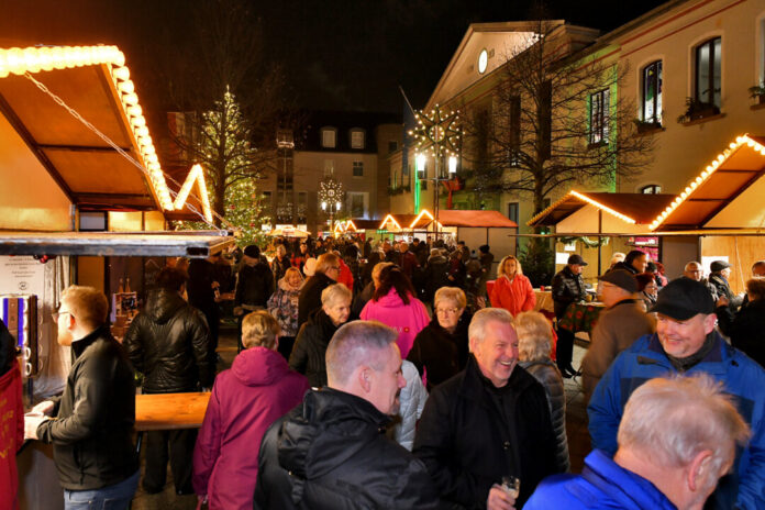 Weihnachtsmarkt bei Nacht mit Besuchern und Beleuchtung.