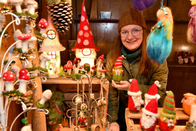 Frau präsentiert handgemachte Weihnachtsdeko auf Markt.