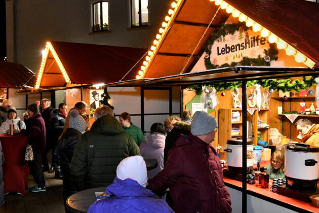 Weihnachtsmarktstand mit Menschen und Beleuchtung