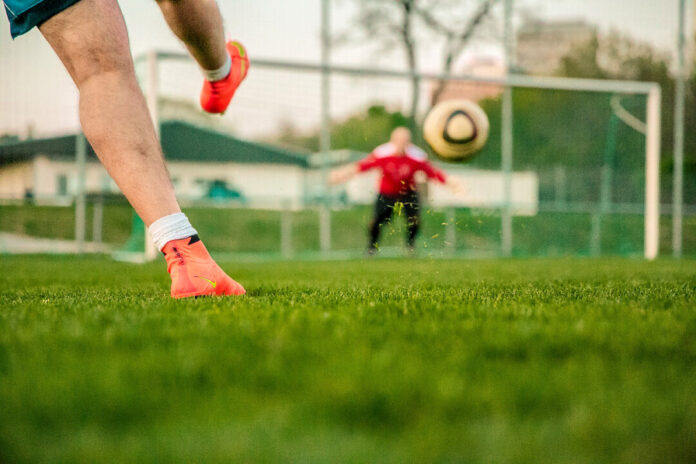 Fußballspieler tritt Ball im Tor.