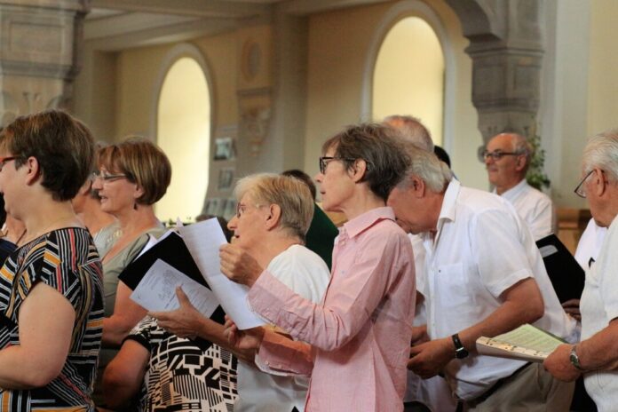 Menschen singen in Kirche mit Gesangbüchern.