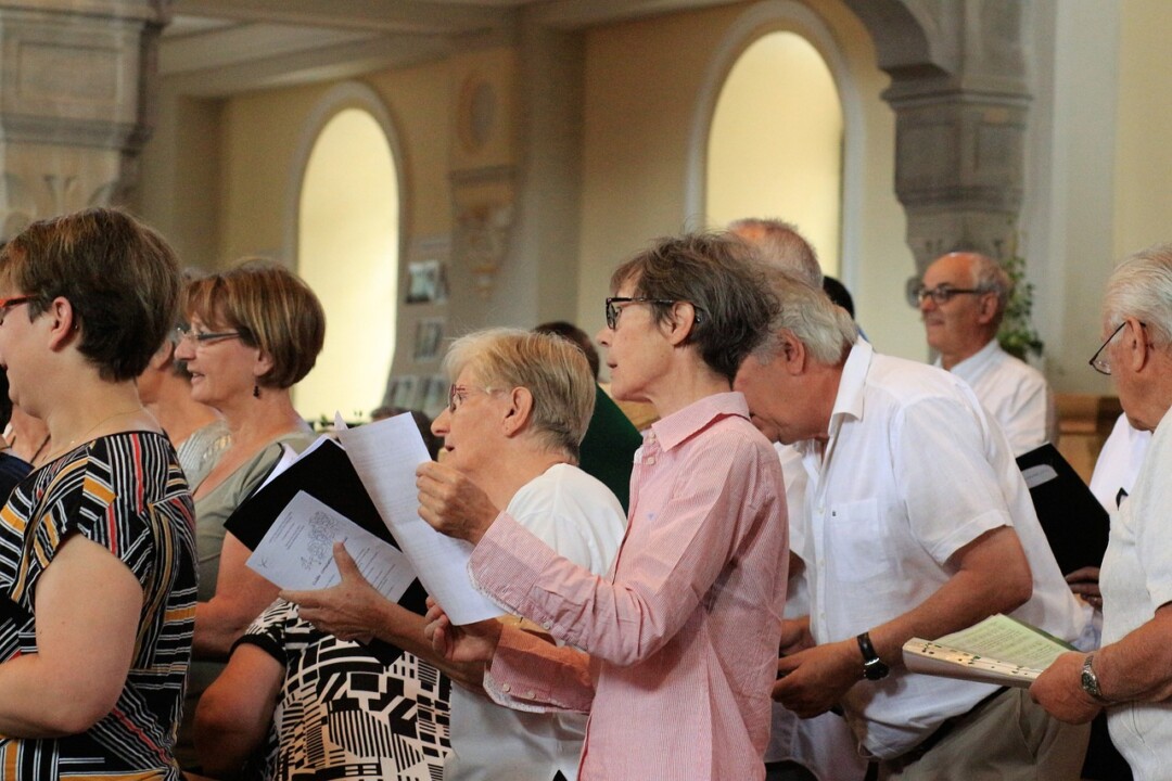 Menschen singen in Kirche mit Gesangbüchern.
