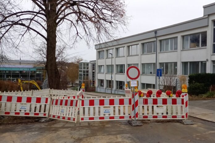 Baustelle vor Schulgebäude mit Absperrung.