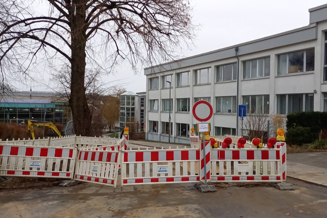 Baustelle vor Schulgebäude mit Absperrung.