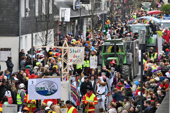 Karnevalsumzug mit verkleideten Menschen und Festwagen.