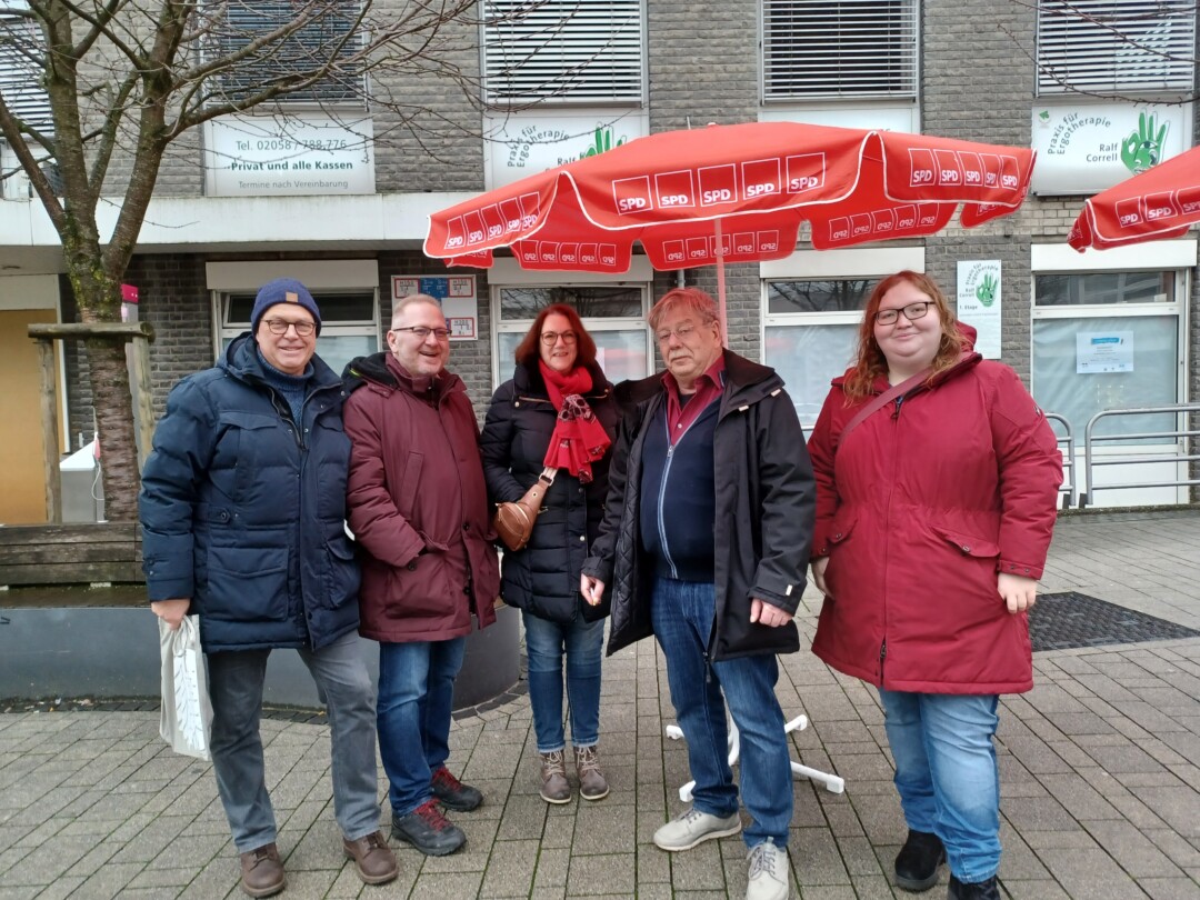 Fünf Personen vor Geschäft mit SPD-Sonnenschirmen.