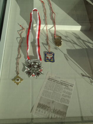 Medaillen und Zeitungsausschnitt in Vitrine