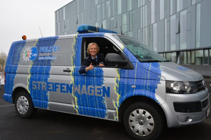 Polizeibeamtin lächelt im Streifenwagen.