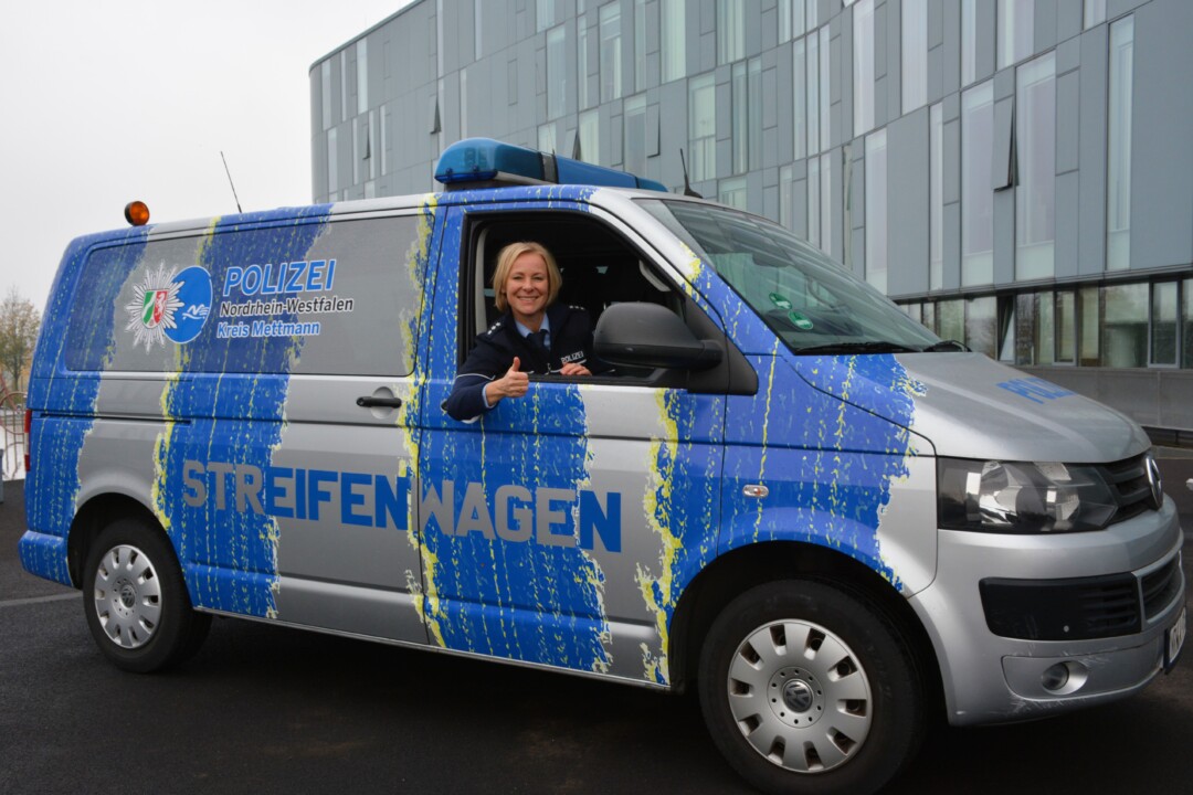 Polizeibeamtin lächelt im Streifenwagen.
