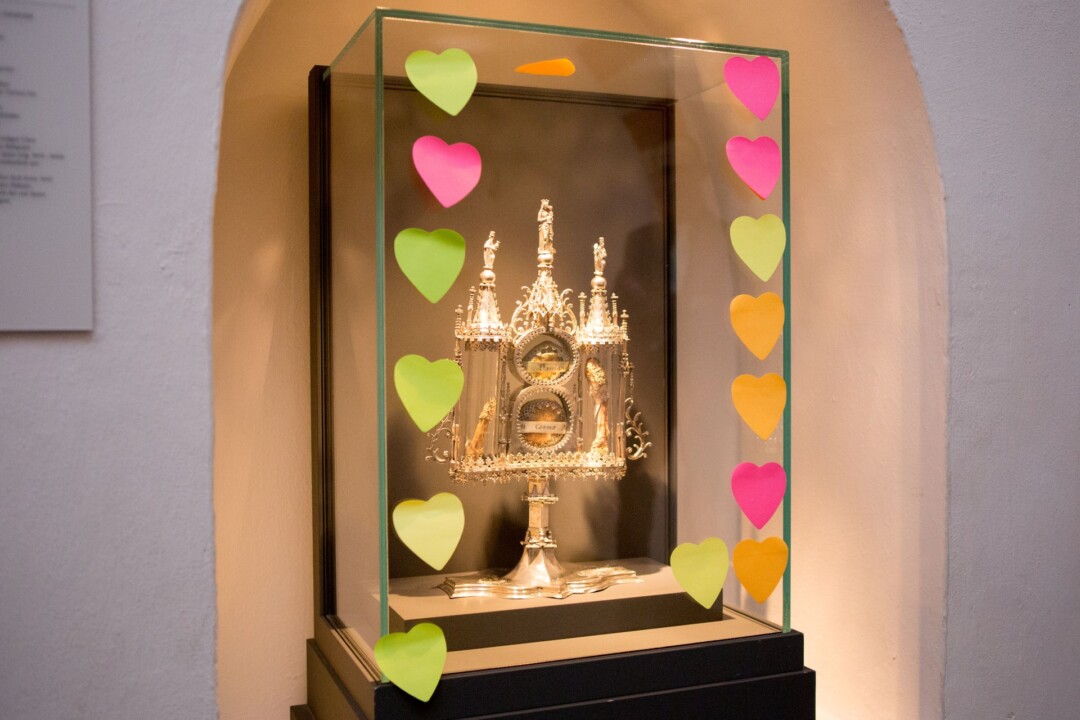 Reliquiar in Vitrine mit bunten Herzen dekoriert.