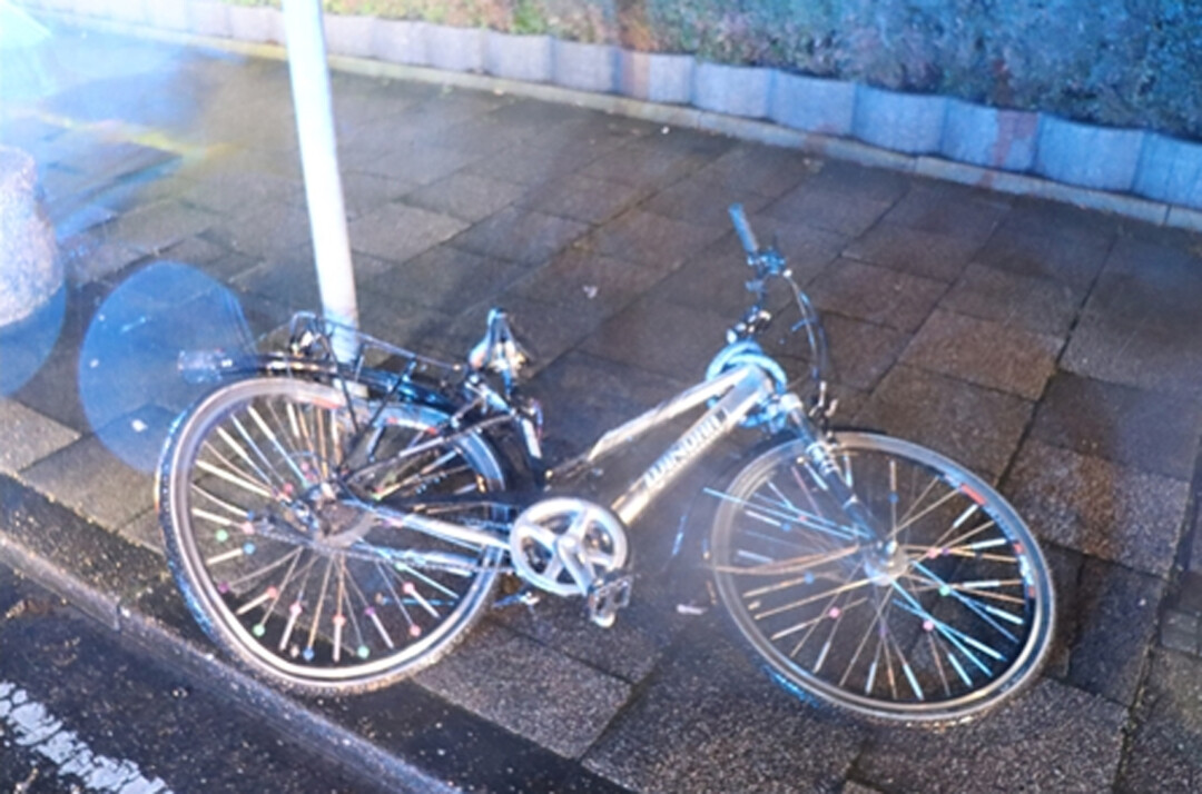 Umgefallenes Fahrrad bei Nacht auf Gehweg.