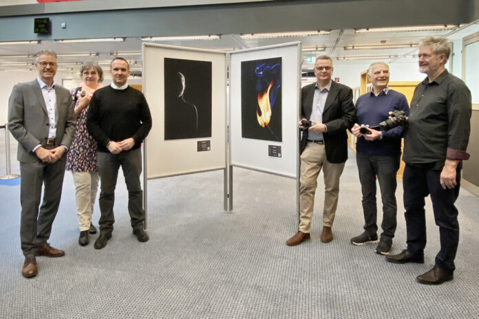 Personen vor Kunstausstellung mit Fotografien.