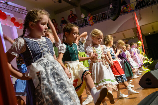 Kinder in Trachten tanzen auf Bühne.