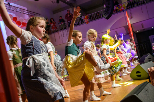 Kinder tanzen auf Bühne bei Schultheateraufführung.