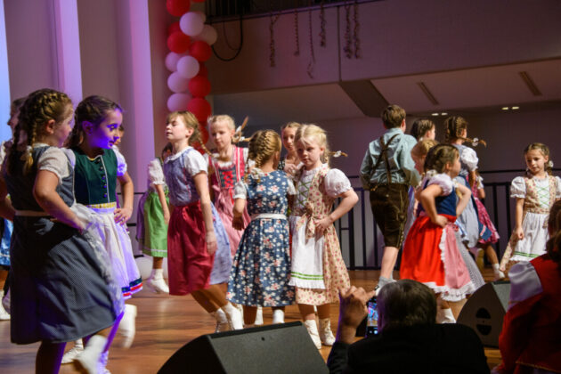 Kinder tanzen in Trachten bei Festveranstaltung.
