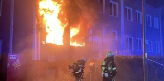 Feuerwehrleute löschen nächtlichen Gebäudebrand.