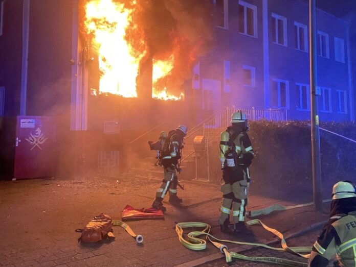 Feuerwehrleute löschen nächtlichen Gebäudebrand.