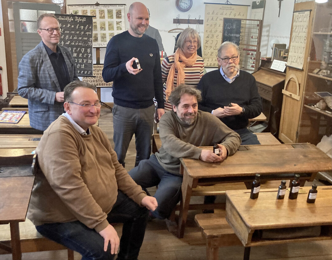 Gruppe in historischem Klassenzimmer lächelt.