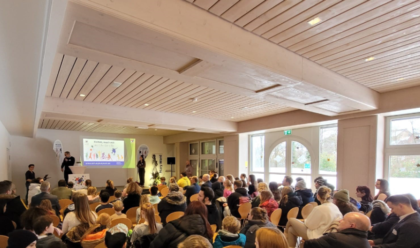 Konferenzraum mit Zuschauern und Präsentation.