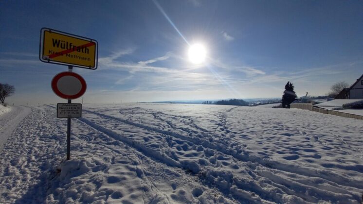 Winterlandschaft mit Ortsschild Wülfrath, verschneiter Weg.