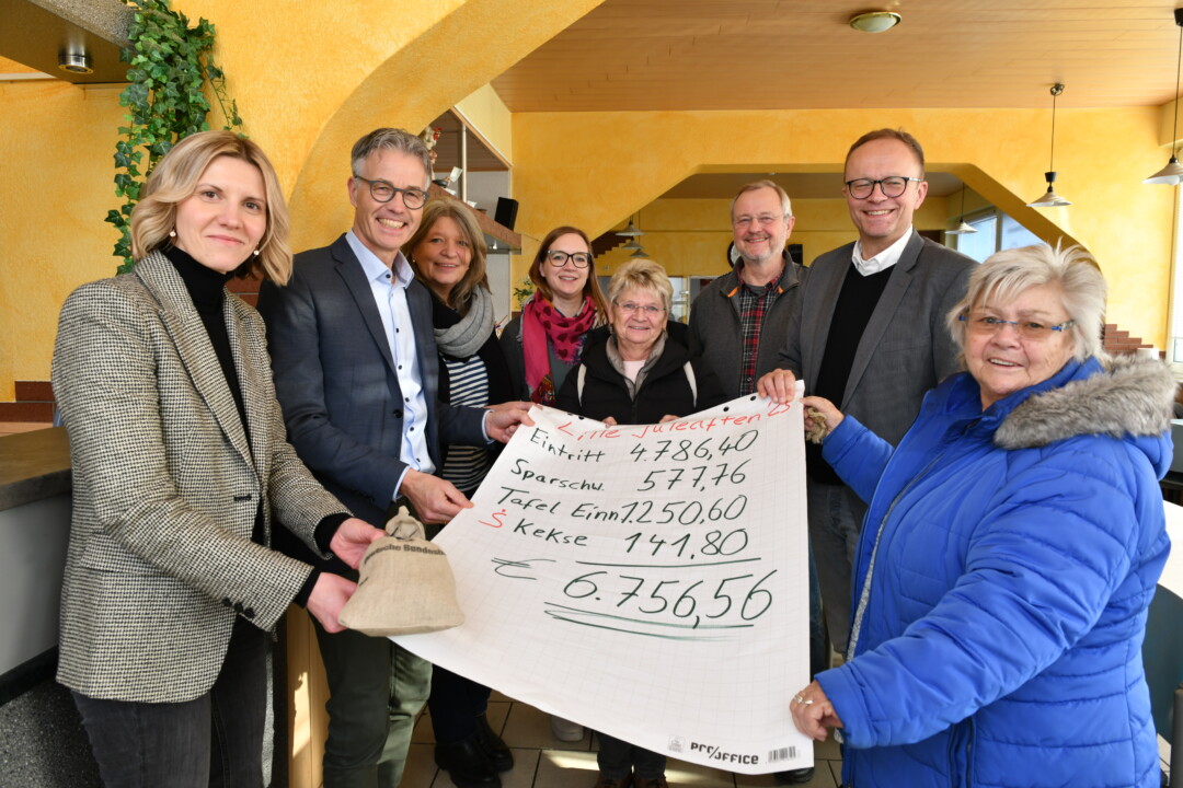 Gruppe hält Spendenscheck in Empfang.