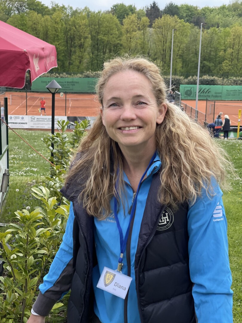 Frau lächelt auf einem Tennisplatz.
