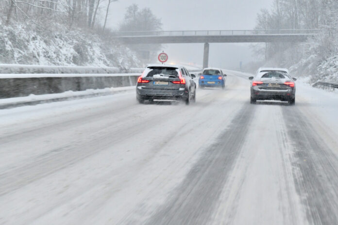 Autos fahren auf verschneiter Straße im Winter.