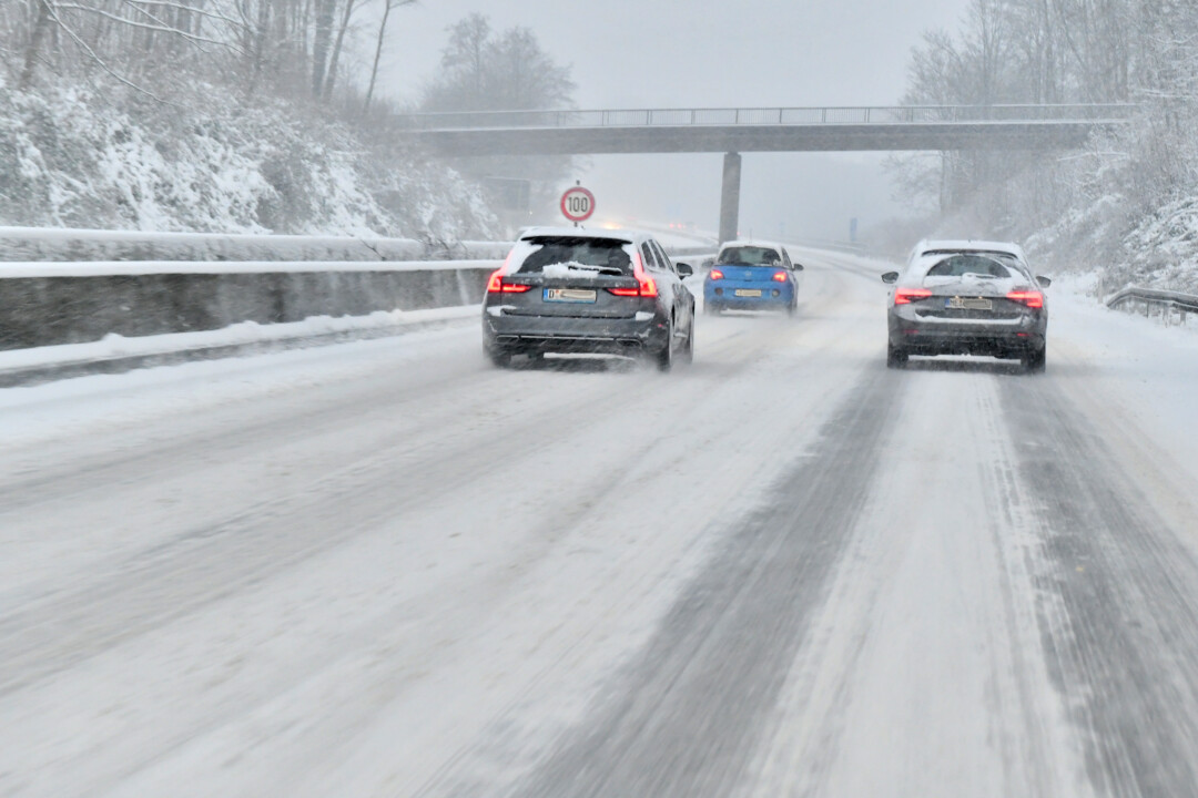 Autos fahren auf verschneiter Straße im Winter.