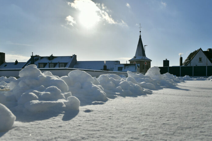 Schneebedeckte Dächer mit Kirchturmspitze im Sonnenlicht