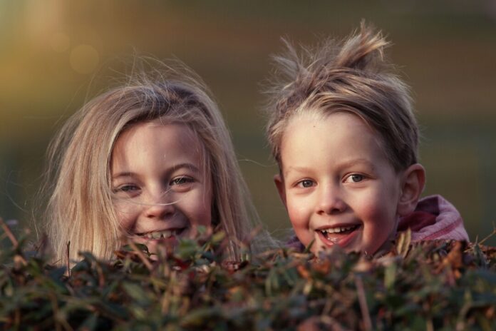 Lachende Kinder hinter Hecken im Sonnenuntergang.