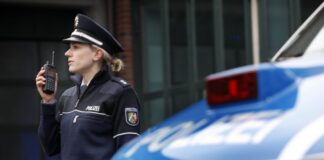 Polizistin mit Funkgerät neben Streifenwagen