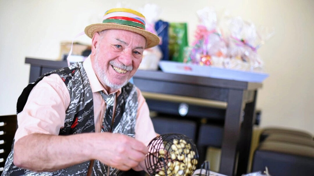 Fröhlicher Mann spielt Bingo mit buntem Hut.