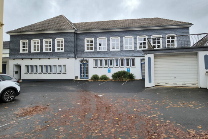 Grau verkleidetes Gebäude mit Parkplatz und Garage