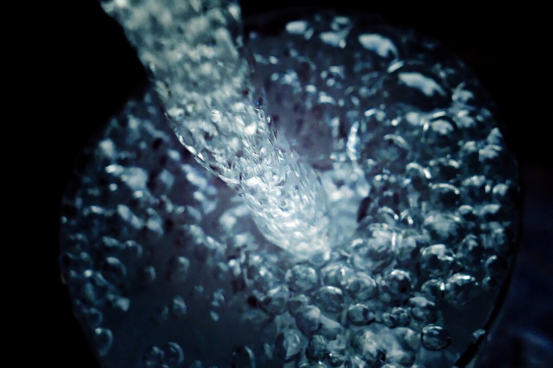 Sprudelndes Wasser in einem Glas, Nahaufnahme, blaue Töne.