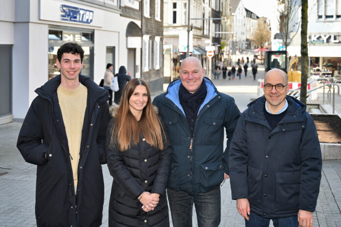 Vier Personen lächeln in der Stadtstraße.