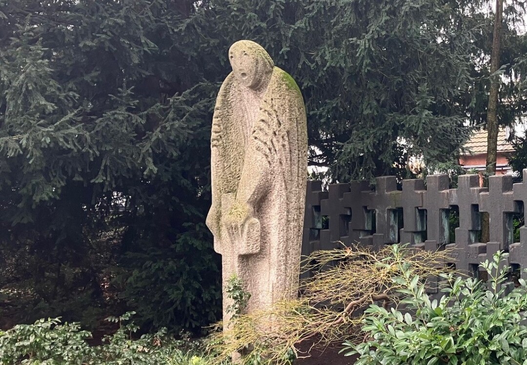 Steinskulptur eines Engels in einem Garten.