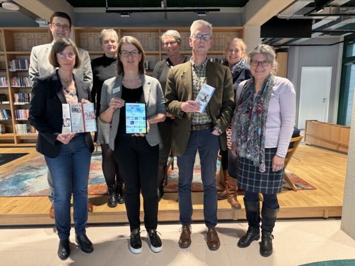 Gruppe zeigt Broschüren in Bibliothek.