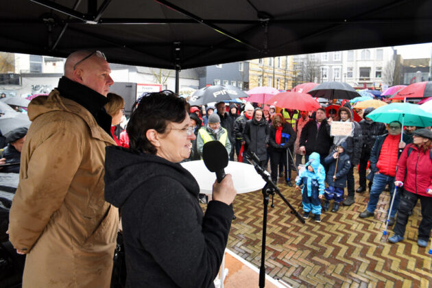Frau hält Rede bei regnerischer Demonstration in Deutschland.
