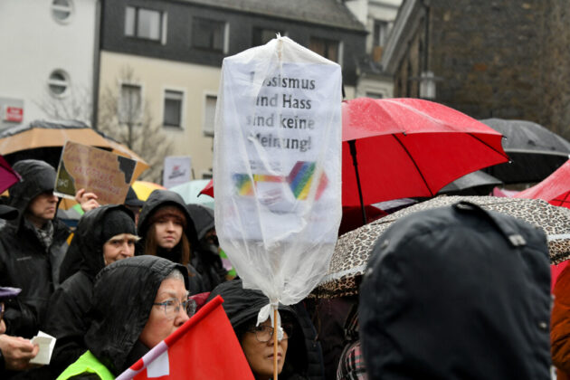 Demonstration gegen Rassismus unter Regenschirmen.