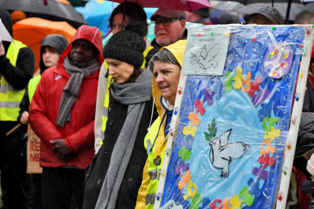 Demonstrationsteilnehmer im Regen mit Transparent.