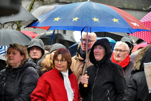 Menschen mit Regenschirmen bei einer Versammlung in Europa.