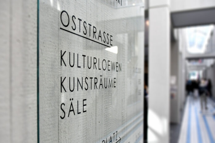 Wand mit Text "Oststraße" und "KulturLöwen" in Passage.