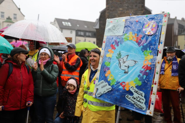 Menschen mit Transparent bei Friedensdemonstration im Regen