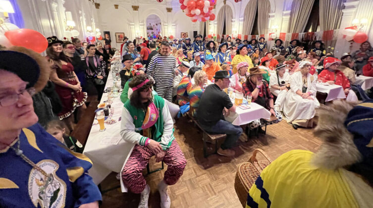 Karnevalsfeier mit kostümierten Menschen in einem Saal.