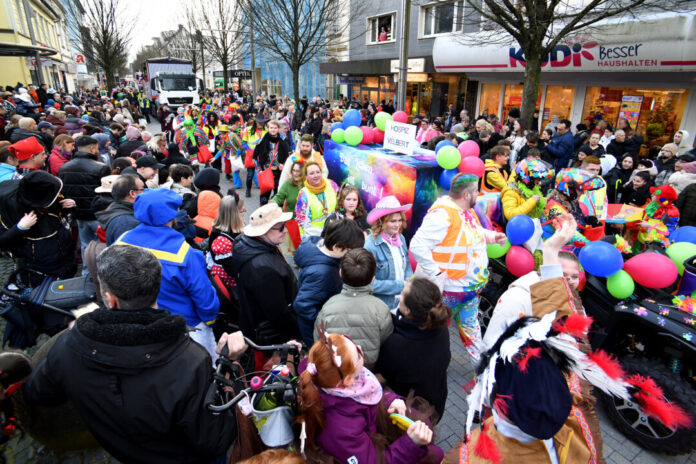 Karnevalsumzug mit kostümierten Menschen und bunten Ballons.