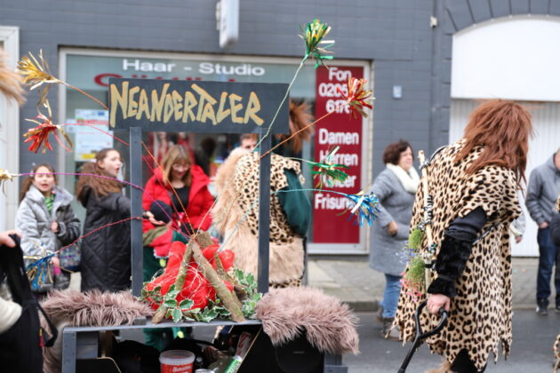Karnevalsumzug mit Neandertaler-Motto und Zuschauern.