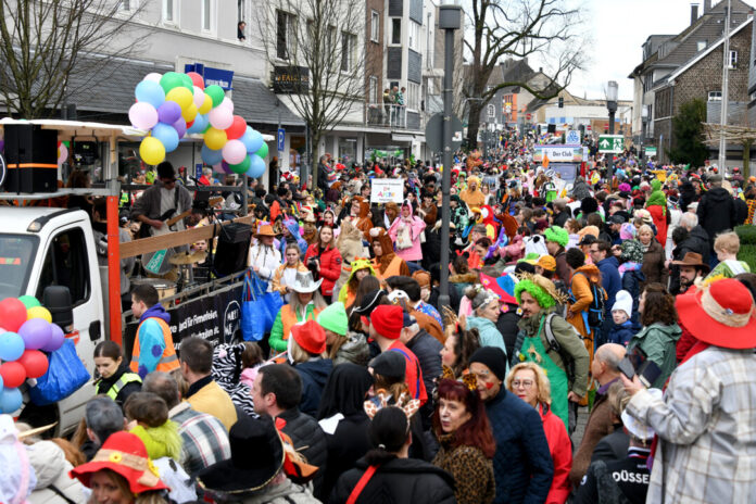 Karnevalsumzug mit kostümierten Menschen und Wagen.